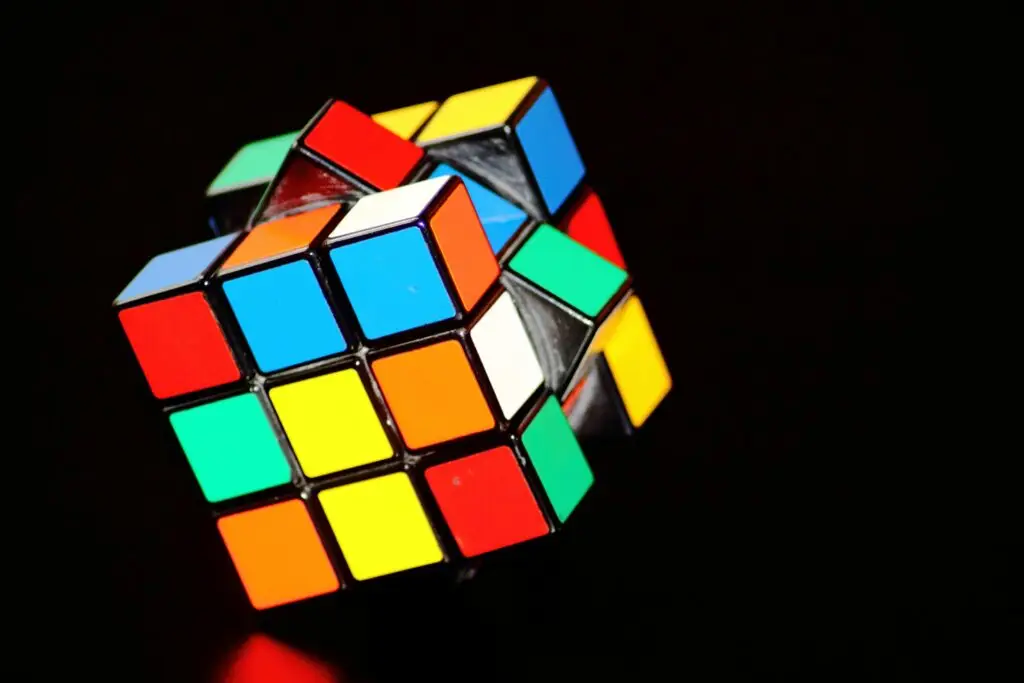 A scrambled, brightly colored Rubik’s Cube floating against a dark black background, symbolizing logic, pattern recognition, and number memory challenges.