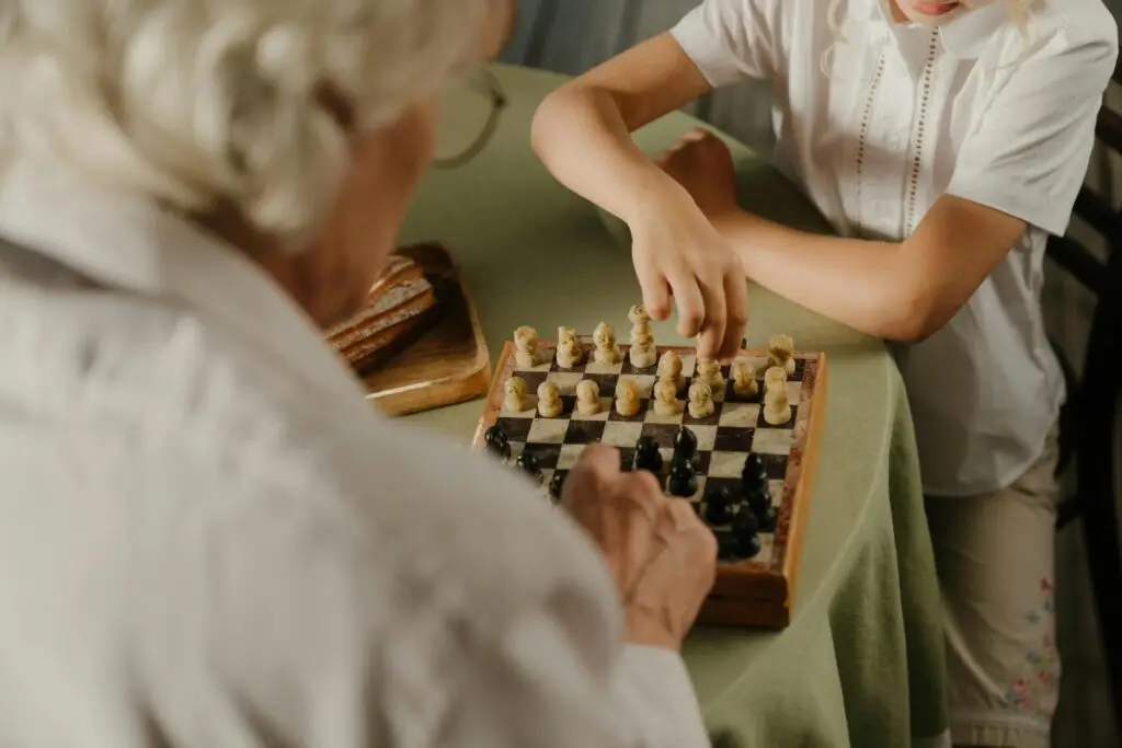 An older adult and a child playing chess together, demonstrating strategic thinking and pattern-based memory skills.